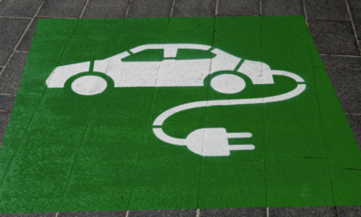 UM desenho no chão mostrando um carro do qual sai um fio de tomada, representando um carro elétrico.