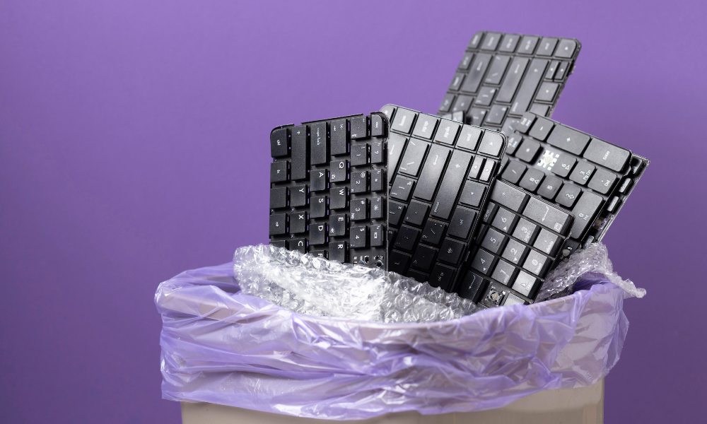 Uma lixeira com diversos teclados de computador.